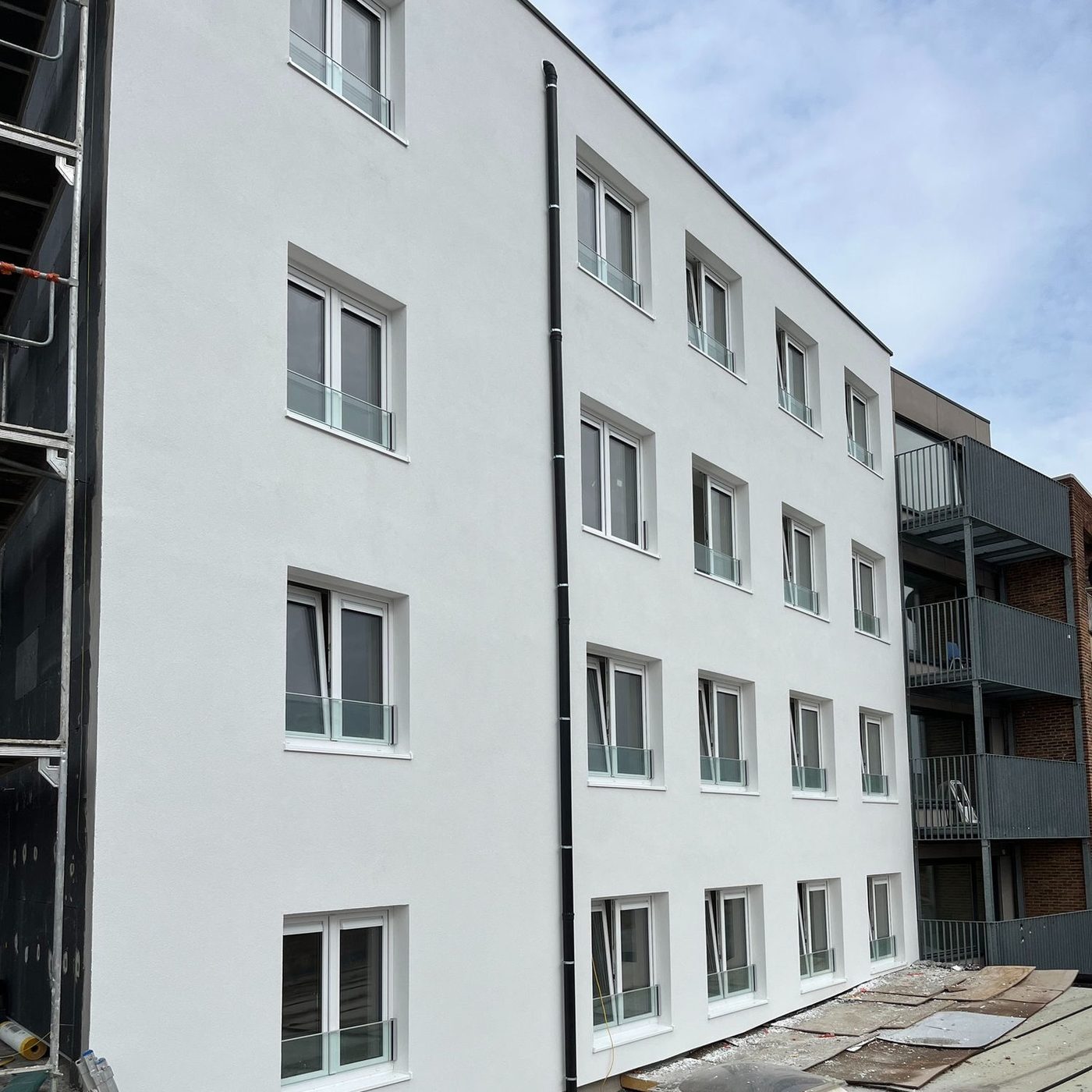 Gerenoveerd appartementsblok met witte crepi en nieuw buitenschrijnwerk