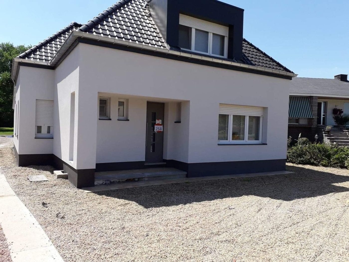 Woning met witte gevelbepleistering en zwarte plint